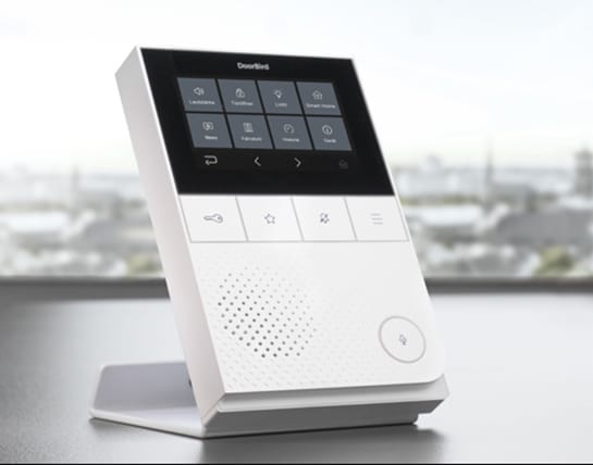 DoorBird A1101 in white on a desk in a home office, on the optional A8003 stand (sold separately)