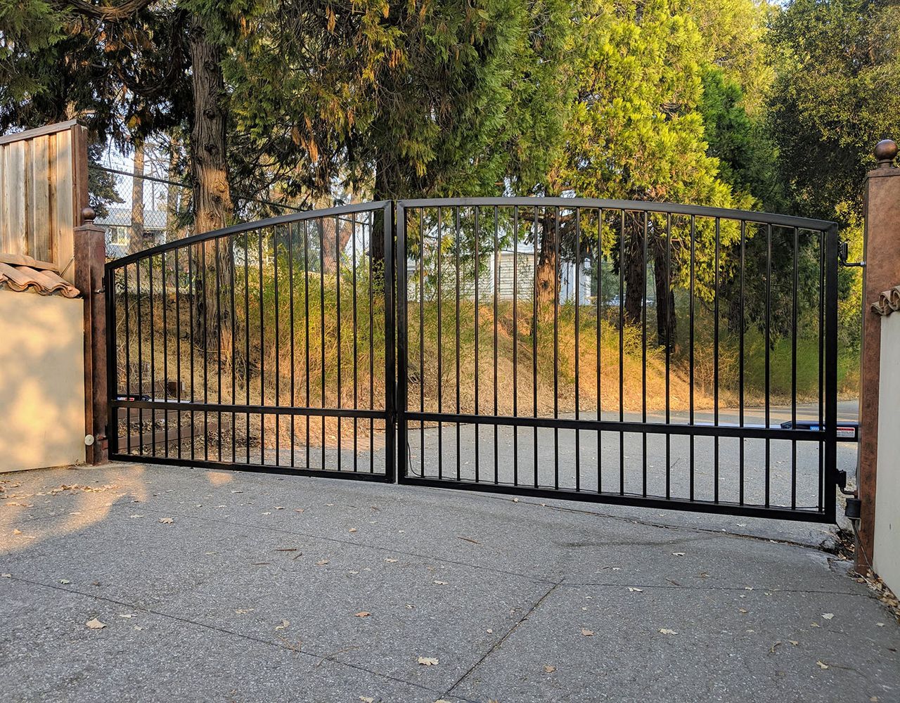 Arched black steel double driveway gate with open vertical pickets